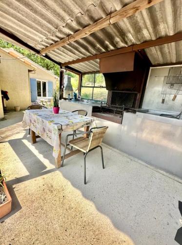 un patio avec une table et un grill dans l'établissement Villa spacieuse, au calme, en bord de rivière, à Lauroux