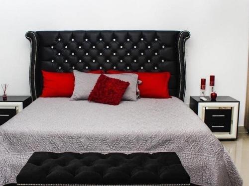 ein Schlafzimmer mit einem großen schwarzen Bett mit roten Kissen in der Unterkunft Casa Moderna Frente Alberca 3 min de la Playa Azul Pacifico in Mazatlán