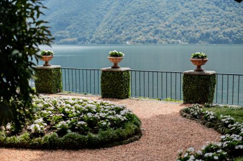 a garden with three vases on a fence near a lake at Fogazzaro Lake View Apartment in Oria