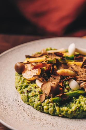 a plate with a pizza with mushrooms and broccoli at JA Palm Tree Court, Dubai in Dubai