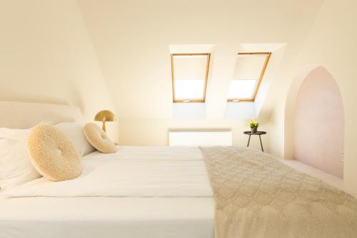 a bedroom with a white bed with two windows at St. George Hotel in Sofia