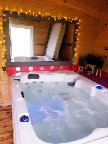 une baignoire dans une pièce avec un miroir et des lumières dans l'établissement Cozy Tiny House plus SPA - à Pereille d'en Haut, à Péreille