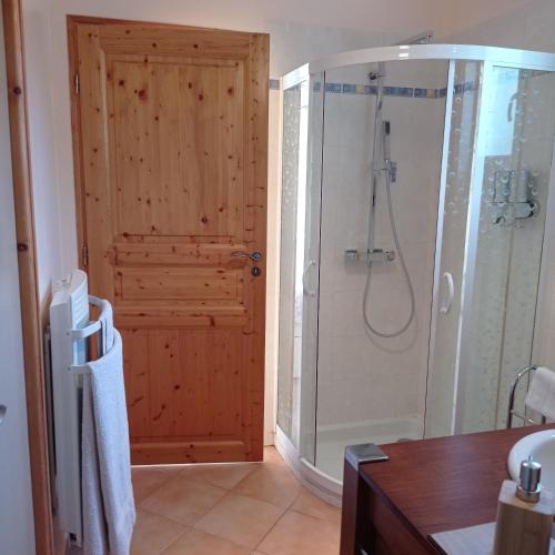 La salle de bains est pourvue d'une douche et d'une porte en bois. dans l'établissement Chambre Studette indépendante, à Briançon