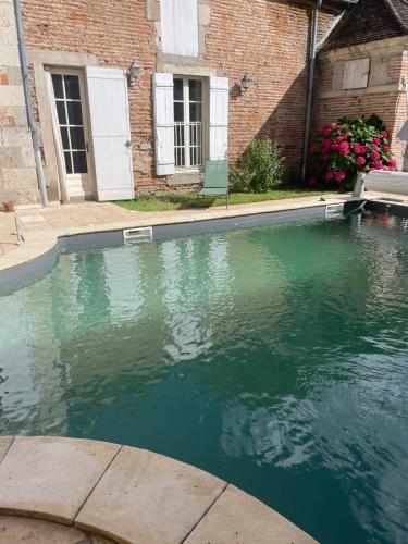 une piscine devant un bâtiment en briques dans l'établissement Château de Ferrègues - L'appart, à Tonneins