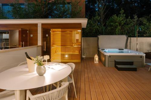 a deck with a table and a bath tub at The Q Whisper - new deluxe hideaway with sauna, jacuzzi and a garage in Rovinj