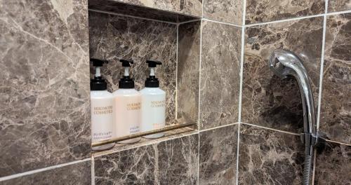 a bathroom with three bottles of soap on a wall at Villa The Club 御殿場ウエスト in Gotemba