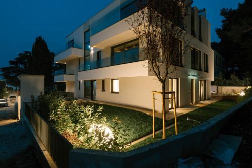 a house with a garden in front of it at night at The Q Whisper - new deluxe hideaway with sauna, jacuzzi and a garage in Rovinj