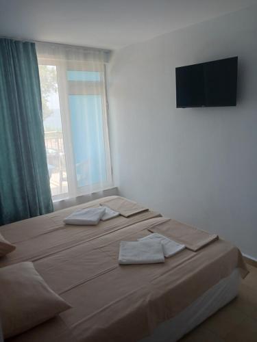 two beds in a room with a window and a television at хотел Ропотамо in Primorsko