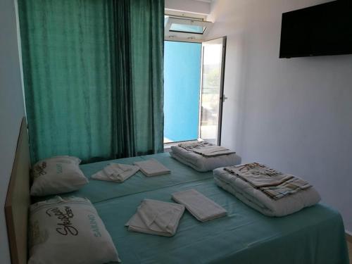 a bed with three pillows on top of it at хотел Ропотамо in Primorsko