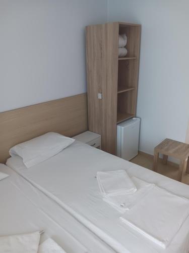 a bedroom with a white bed and a wooden cabinet at хотел Ропотамо in Primorsko