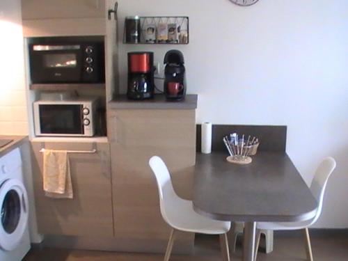 une cuisine avec une table et des chaises et un micro-ondes dans l'établissement Henri IV, à Barbotan-les-Thermes