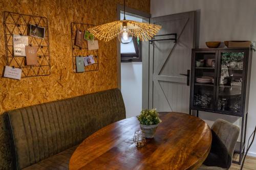 a dining room with a wooden table and a chandelier at Wellness in the Woods - 4p TinyHouse met privé sauna & hottub in Diessen