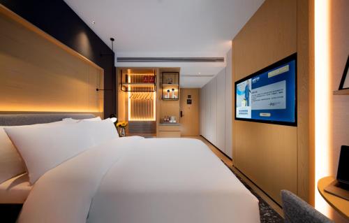 a bedroom with a large white bed and a tv at Park Inn by Radisson, Nanchang Honggutan Wanda Plaza Twin Towers in Nanchang