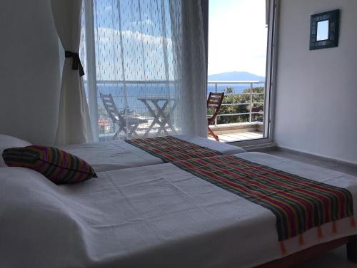 a bed in a room with a large window at Assos Gardenya Butik Otel in Ayvacık