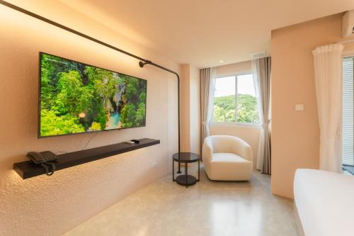 a living room with a tv on a wall at Mai Hotel Chiang Mai in Chiang Mai