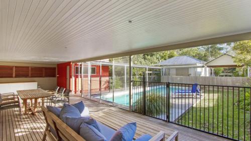 a deck with a couch and a table and a pool at Sand & Sea - Pearl Beach With Pool in Pearl Beach