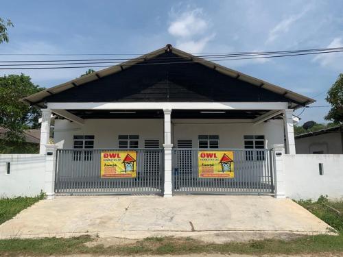 a white building with a gate with signs on it at Nana OWL Homestay A & B Roomstay C & D in Kemasik