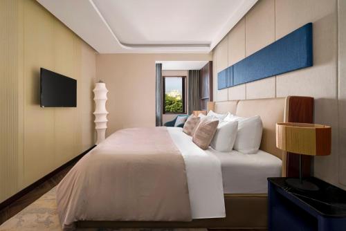 a bedroom with a white bed and a television at Signature by M Village Thợ Nhuộm in Hanoi