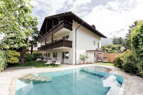 a house with a swimming pool in front of a house at Hotel Garni Sirmian in Merano