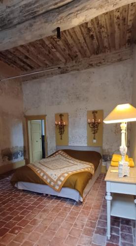 a bedroom with a bed and a table with a lamp at Logis La Vachère in Avallon