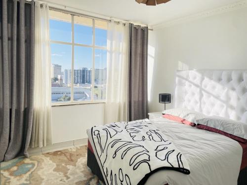 a bedroom with a bed and a large window at Villa Saarchi Apartments in Windhoek