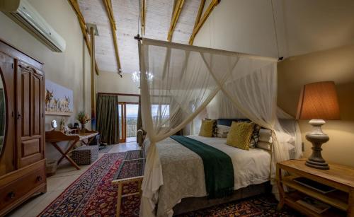 a bedroom with a bed with a canopy at De Zeekoe Guest Farm in Oudtshoorn