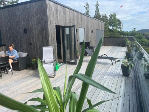 a woman sitting on the deck of a house at Arendalsuka Vacation Norway in Froland Verk