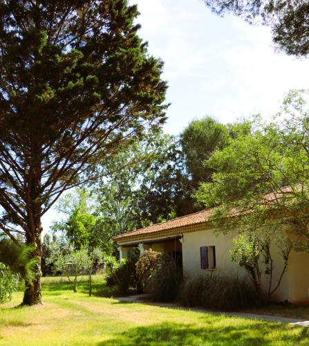 a house in a yard with trees and grass at Le Mas Des Sables in Aigues-Mortes
