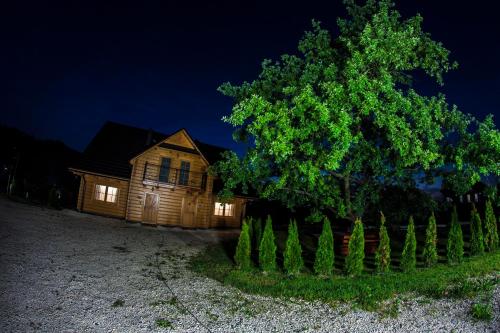 a wooden house with a tree in front of it at Chatka Pod Laskiem - Domki w górach in Soblówka