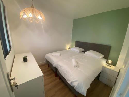 - une chambre avec un lit blanc et un lustre dans l'établissement Appartement bassin de la villette, à Paris