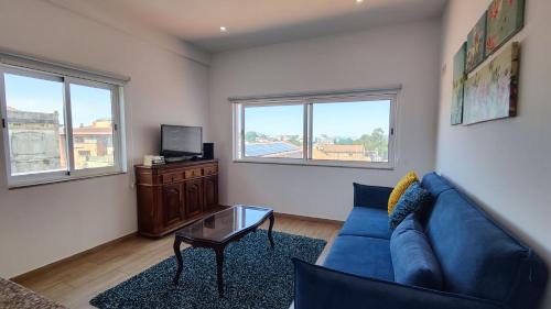 a living room with a blue couch and two windows at O'Porto Cheers Gaia in Vila Nova de Gaia
