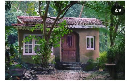 a small house with a wooden door in a forest at SB Vacations & Homes in Kalimpong