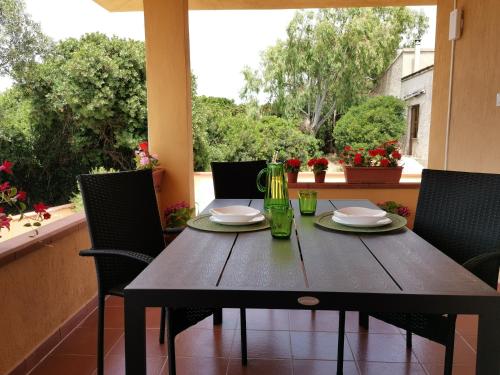 a wooden table with plates and glasses on a balcony at Casa Sofia in Putzu Idu