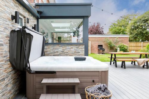 an outdoor hot tub on a deck with a table at Coastal Retreat for 10 with Hot Tub in West Wittering