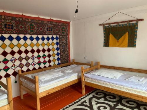two beds in a room with a painting on the wall at Naryn Guest House in Naryn
