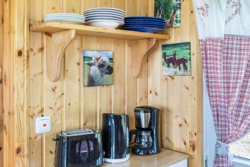 a kitchen with a wooden wall with plates and appliances at Tinyhouse Alpakawiese in Schlitz