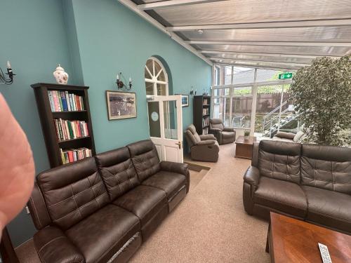 a living room with leather couches and a book shelf at Long Quay House in Kinsale