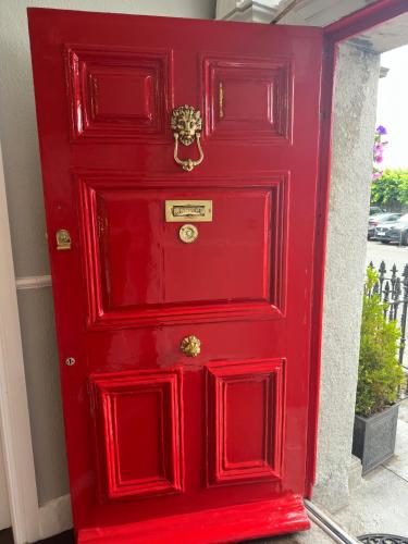 a red door with a gold knocker on it at Long Quay House in Kinsale