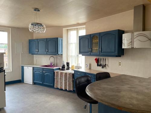 une cuisine avec des placards bleus et une table avec des chaises dans l'établissement maison de ville dans le perche, à Senonches