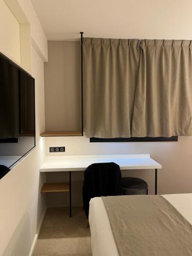 a bedroom with a desk and a bed and a television at Hôtel Le Relais des Brasseurs - Aubagne in Aubagne