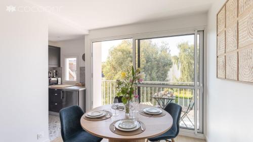ein Esszimmer mit Tisch und Stühlen und einem großen Fenster in der Unterkunft Le Vauban - A 15min à pied de la plage in Dinard