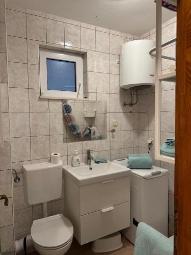 a bathroom with a white toilet and a sink at Apartments Eti in Bol