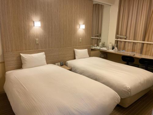 a hotel room with two beds and a desk at Smile Hotel Shirakawa in Nishigo