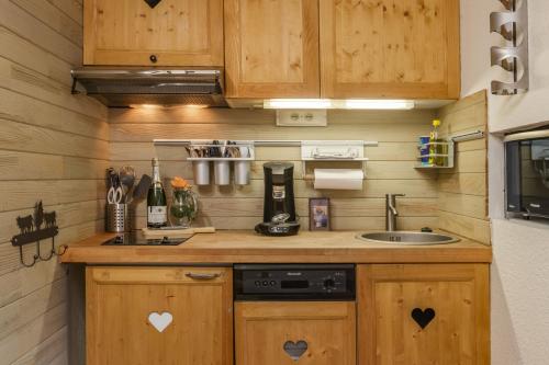 Elle comprend une petite cuisine avec des placards en bois et un évier. dans l'établissement Chamonix Sud - Balme 407 Happy Rentals, à Chamonix-Mont-Blanc
