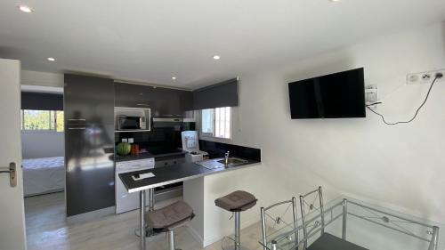 - une cuisine avec un comptoir avec des tabourets et une télévision murale dans l'établissement NEMO Sanary, à Sanary-sur-Mer