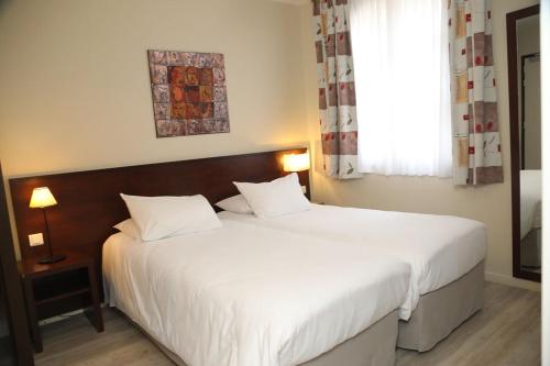 a bedroom with two white beds and a window at Hôtel de l'Abbaye des Prémontrés in Pont-à-Mousson