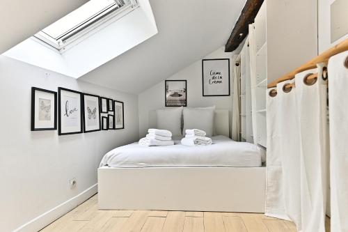 une chambre blanche avec un lit avec des serviettes dessus dans l'établissement Appartement paisible et central Rivoli - II, à Paris