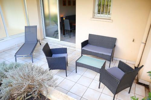 un groupe de chaises et de tables sur une terrasse dans l'établissement Appartement 202 - LES SUITES DE ROBINSON - Résidence avec piscine en bord de Siagne, à Mandelieu-La-Napoule, à Mandelieu-la-Napoule
