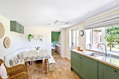 a kitchen with green cabinets and a sink and a table at Chantry Cottage - Newby Hall, Ripon, North Yorkshire in Copt Hewick