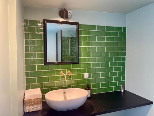 a green tiled bathroom with a sink and a mirror at Faaborg Bed and Breakfast in Fåborg